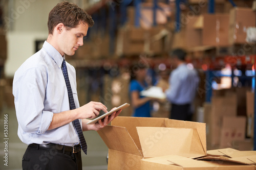 Photo: Manager In Warehouse Checking Boxes Using Digital Tablet Manager In Warehouse Checking Boxes Using Digital Tablet