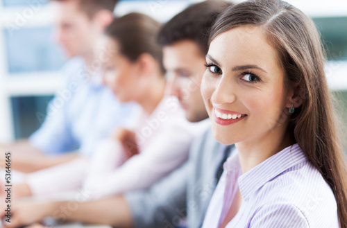 Photo: Businesswoman with coworkers in background Businesswoman with coworkers in background