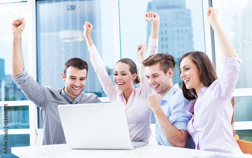 Photo: Business people cheering at laptop Business people cheering at laptop