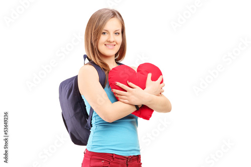 Photo: Female student with backpack holding a red heart Female student with backpack holding a red heart