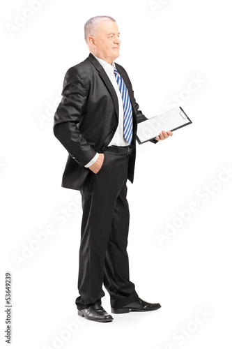 Photo: Full length portrait of a mature businessman posing with clipboa Full length portrait of a mature businessman posing with clipboa