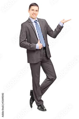 Photo: Full length portrait of a young businessman leaning against wall Full length portrait of a young businessman leaning against wall