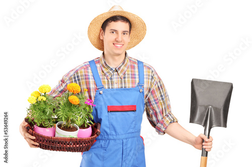 Photo: Male agricultural worker holding a shovel and flowers Male agricultural worker holding a shovel and flowers