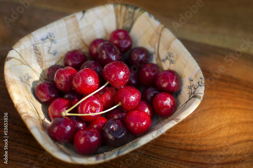 Photo: Ripe cherries in a rustic recipient on a wooden surface. Ripe cherries in a rustic recipient on a wooden surface.