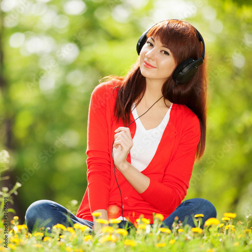 Photo: Happy woman with headphones relaxing in the park Happy woman with headphones relaxing in the park
