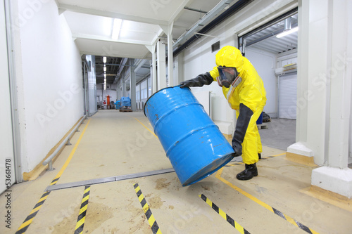 Photo: technician in uniform rolling barrel with hazardous substance technician in uniform rolling barrel with hazardous substance