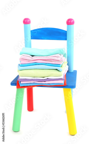 Photo: Small and colorful chair with baby clothes isolated on white Small and colorful chair with baby clothes isolated on white