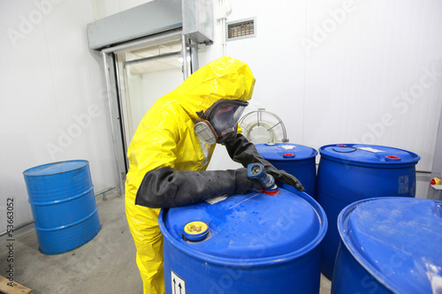Photo: Professional in uniform filling barrels with chemicals Professional in uniform filling barrels with chemicals