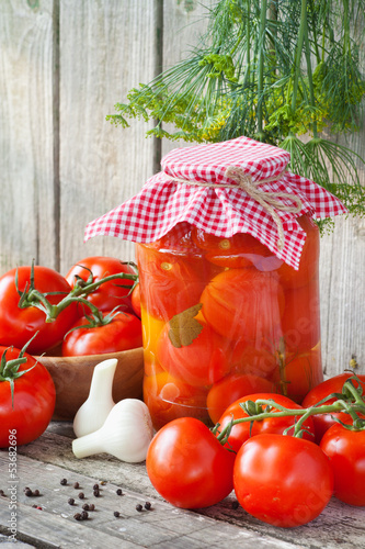Photo: Homemade tomatoes preserves in glass jar. Fresh and canned tomat Homemade tomatoes preserves in glass jar. Fresh and canned tomat