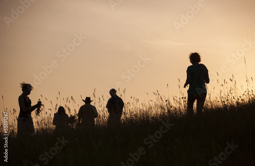 Photo: Silhouettes of People picking flowers during midsummer soltice Silhouettes of People picking flowers during midsummer soltice