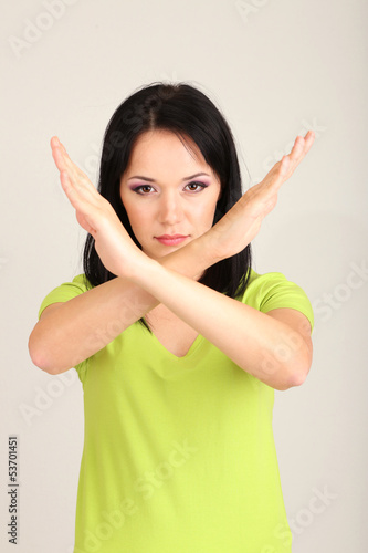 Photo: Girl showing stop sign on grey background Girl showing stop sign on grey background