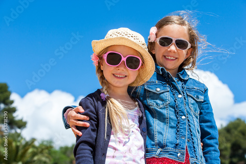 Photo: Two girlfriends wearing sunglasses outdoors. Two girlfriends wearing sunglasses outdoors.