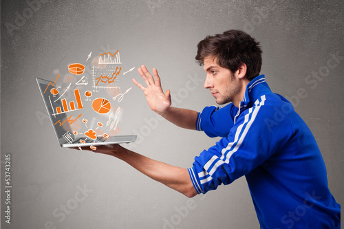 Photo: Handsome man holding laptop with graphs and statistics Handsome man holding laptop with graphs and statistics
