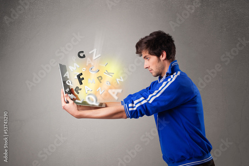 Photo: Attractive young man hoding notebook with colorful letters Attractive young man hoding notebook with colorful letters