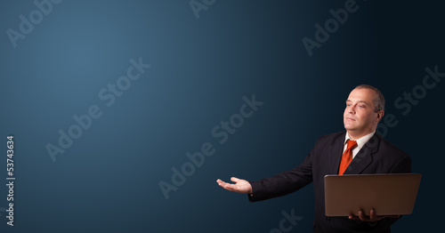 Photo: businessman holding a laptop and presenting copy space businessman holding a laptop and presenting copy space