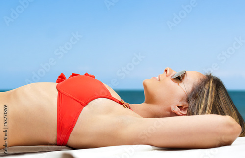 Photo: Woman in bikini relaxing at the beach Woman in bikini relaxing at the beach