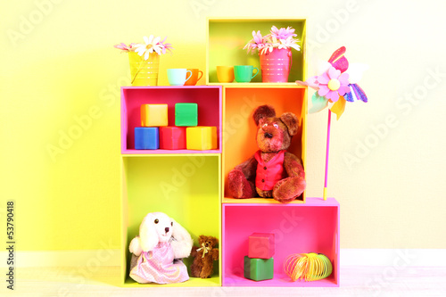 Photo: Bright shelves of different colors with toys on wall background Bright shelves of different colors with toys on wall background