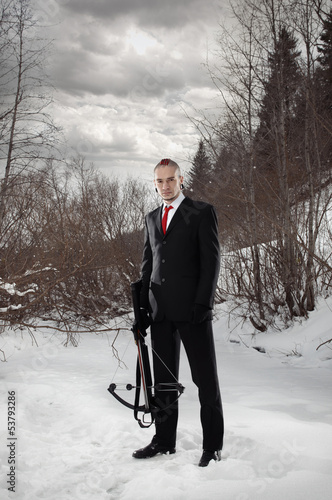 Photo: Hitman with a crossbow in an outdoor setting. Walking Dead Hitman with a crossbow in an outdoor setting. Walking Dead
