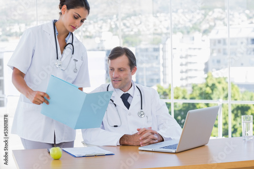 Photo: Doctor showing a folder to a colleague Doctor showing a folder to a colleague