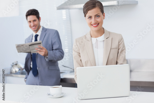 Photo: Businesswoman using a laptop while having breakfast Businesswoman using a laptop while having breakfast