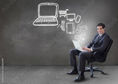 Photo: Businessman typing on his laptop with media device graphics comi Businessman typing on his laptop with media device graphics comi