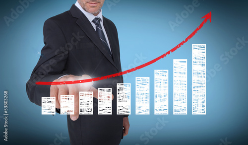 Photo: Businessman touching a chart with a red arrow pointing up Businessman touching a chart with a red arrow pointing up