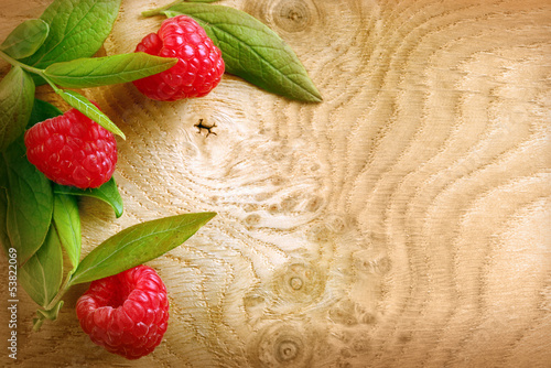 Photo: Ripe red raspberries on a woodgrain texture Ripe red raspberries on a woodgrain texture