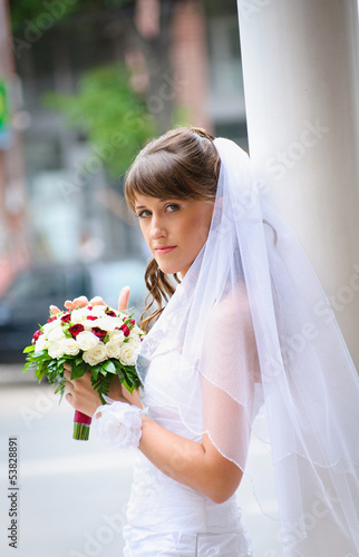 Photo: pensive bride in white dress standing and holding roses bouquet pensive bride in white dress standing and holding roses bouquet