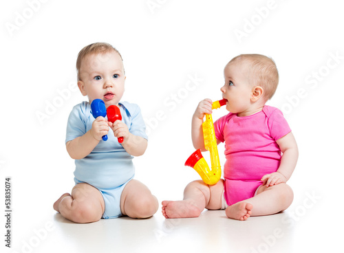 Photo: Babies girl and boy playing musical toys. Isolated on white bac Babies girl and boy playing musical toys. Isolated on white bac