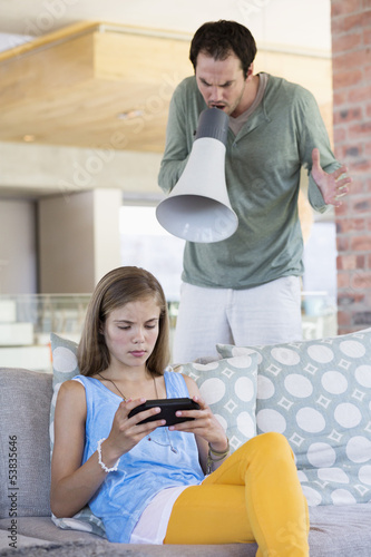 Photo: Man shouting into a megaphone at his daughter for playing video game Man shouting into a megaphone at his daughter for playing video game