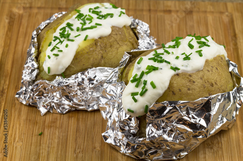 Photo: gebackene Kartoffeln mit Kräuterquark auf Holzbrett gebackene Kartoffeln mit Kräuterquark auf Holzbrett