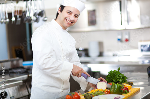 Photo: Friendly chef preparing vegetables in his kitchen Friendly chef preparing vegetables in his kitchen