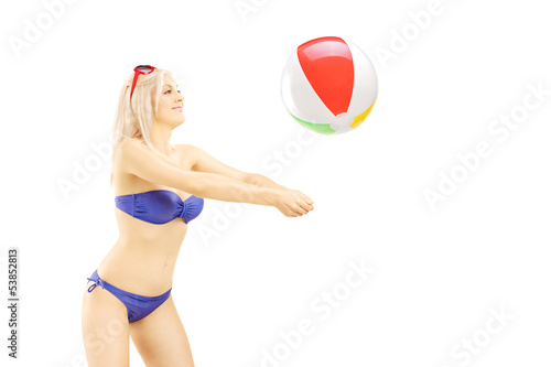 Photo: Young woman in bikini playing with a beach ball Young woman in bikini playing with a beach ball