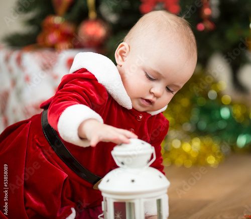 Photo: kid girl dressed as Santa Claus in front of Christmas tree with kid girl dressed as Santa Claus in front of Christmas tree with