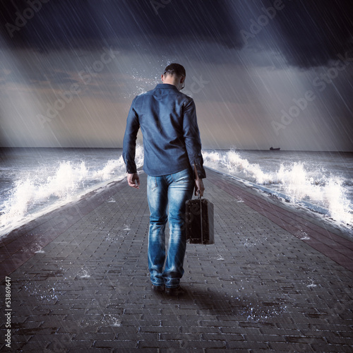 Photo: Young male traveler is on pier during storm Young male traveler is on pier during storm