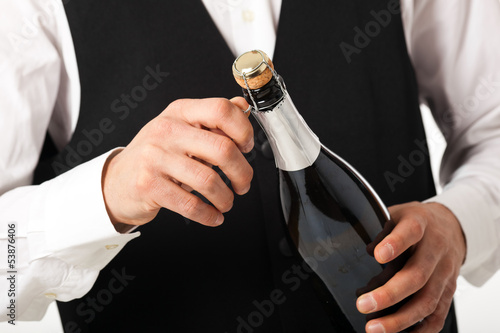 Photo: Portrait of a waiter holding a champagne bottle Portrait of a waiter holding a champagne bottle