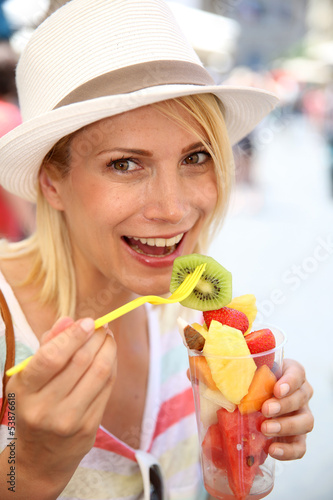 Photo: Cheerful blond girl eating fresh fruits in summer Cheerful blond girl eating fresh fruits in summer