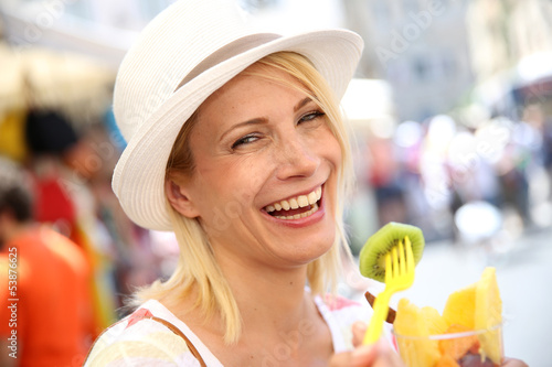 Photo: Cheerful blond girl eating fresh fruits in summer Cheerful blond girl eating fresh fruits in summer