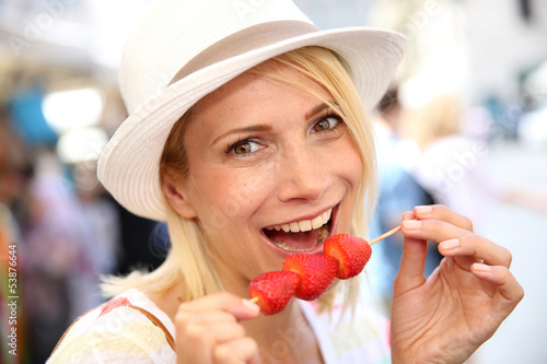 Photo: Cheerful blond girl eating fresh fruits in summer Cheerful blond girl eating fresh fruits in summer