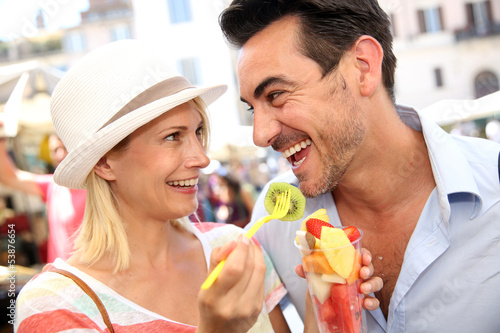 Photo: Couple of tourists having fun eating fresh fruits Couple of tourists having fun eating fresh fruits