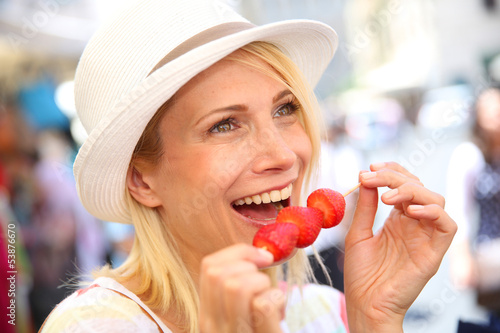 Photo: Cheerful blond girl eating fresh fruits in summer Cheerful blond girl eating fresh fruits in summer