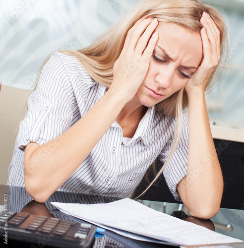Photo: Sad businesswoman looks at the documents Sad businesswoman looks at the documents