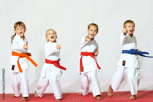 Photo: Four children in kimono hit a punch on a white background Four children in kimono hit a punch on a white background