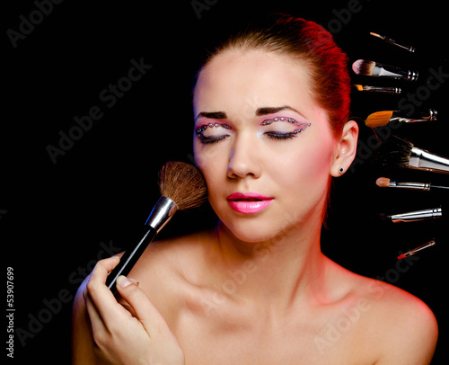 Photo: Beautiful young adult woman holds the make-up brushes Beautiful young adult woman holds the make-up brushes