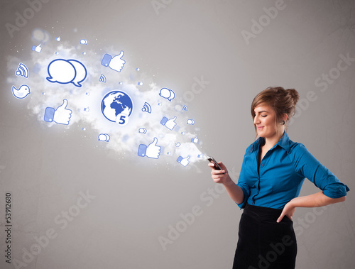 Photo: Pretty young girl holding a phone with social media icons Pretty young girl holding a phone with social media icons