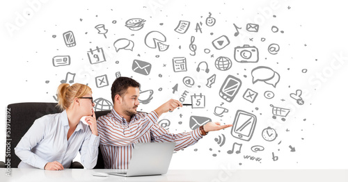 Photo: Businessman and businesswoman with all kind of hand-drawn icons Businessman and businesswoman with all kind of hand-drawn icons