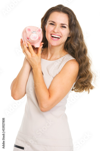 Photo: Happy young woman showing piggy bank Happy young woman showing piggy bank