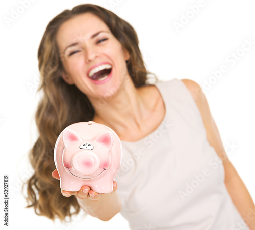 Photo: Closeup on piggy bank in hand of smiling young woman Closeup on piggy bank in hand of smiling young woman