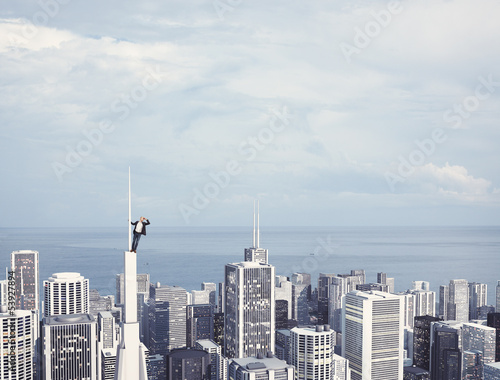 Photo: man on the top of skyscraper looking at the city man on the top of skyscraper looking at the city