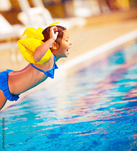 Photo: Little girl jumping into the pool Little girl jumping into the pool